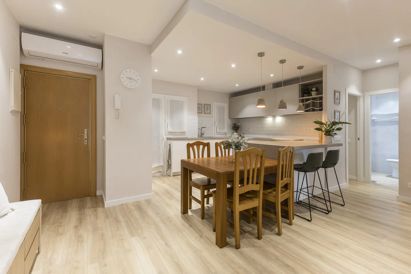 Bright, open-concept apartment with wood floors, a dining table, and a kitchen island with bar stools.