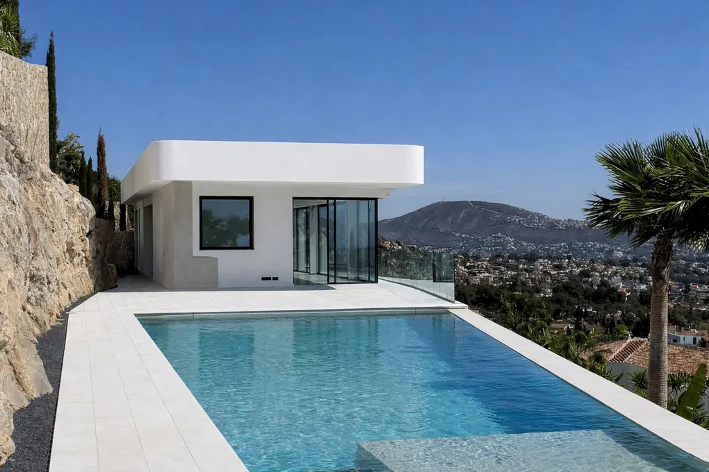 Modern white house with a pool overlooking a city and mountain range under a clear blue sky.