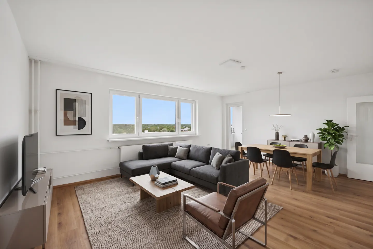 Bright, modern living room with gray sectional, wood floors, dining table, and large window with a view.