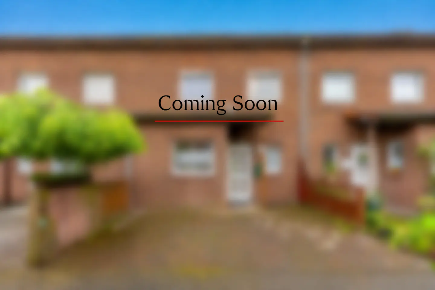 Blurred image of a brick townhouse with "Coming Soon" text overlayed in black with a red underline.