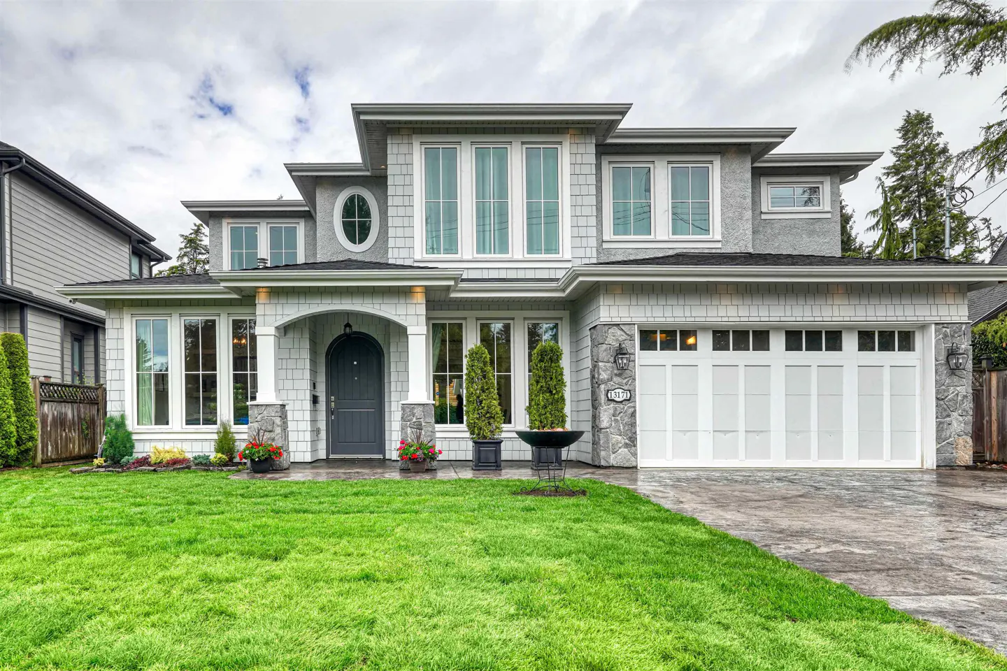 Two-story gray house with white trim, a green lawn, and a two-car garage.