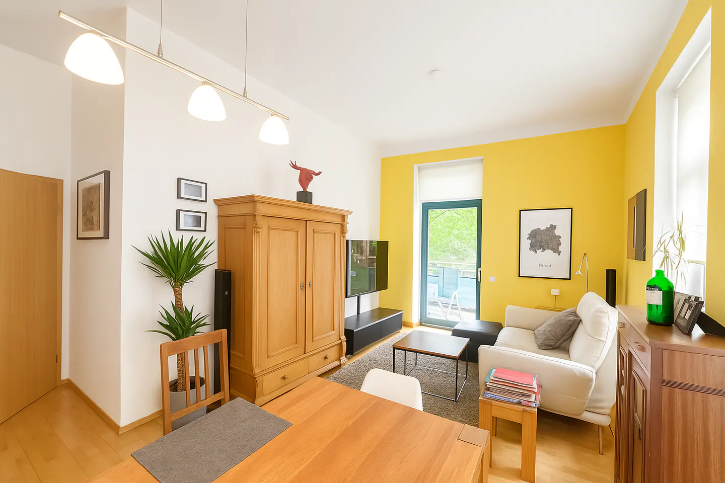 Bright living room with yellow accent wall, white sofa, wood furniture, and balcony access.