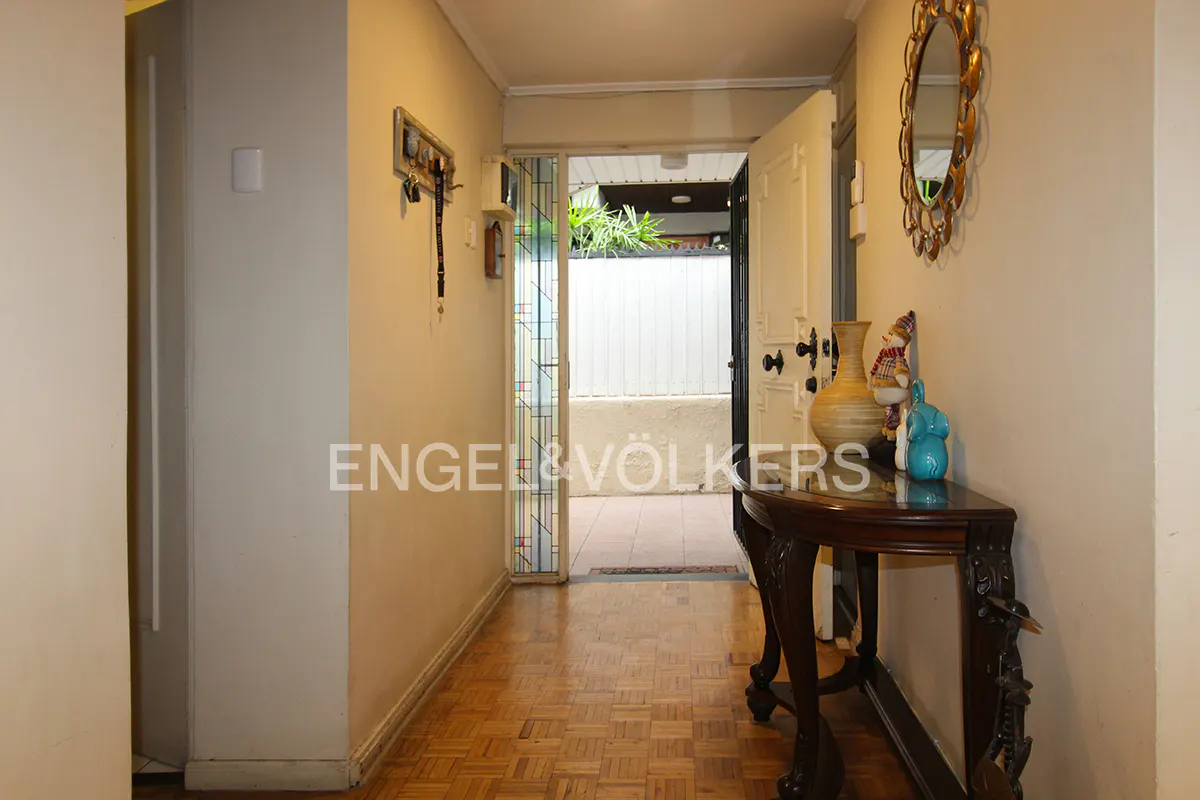 Foyer with parquet floors, a dark wood console table with a vase and figurines, and an open door leading to an outdoor area.