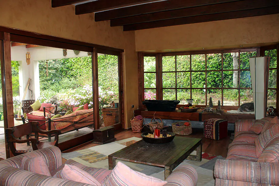 Living room with striped sofas, a wooden coffee table, and a large window overlooking a lush green garden.