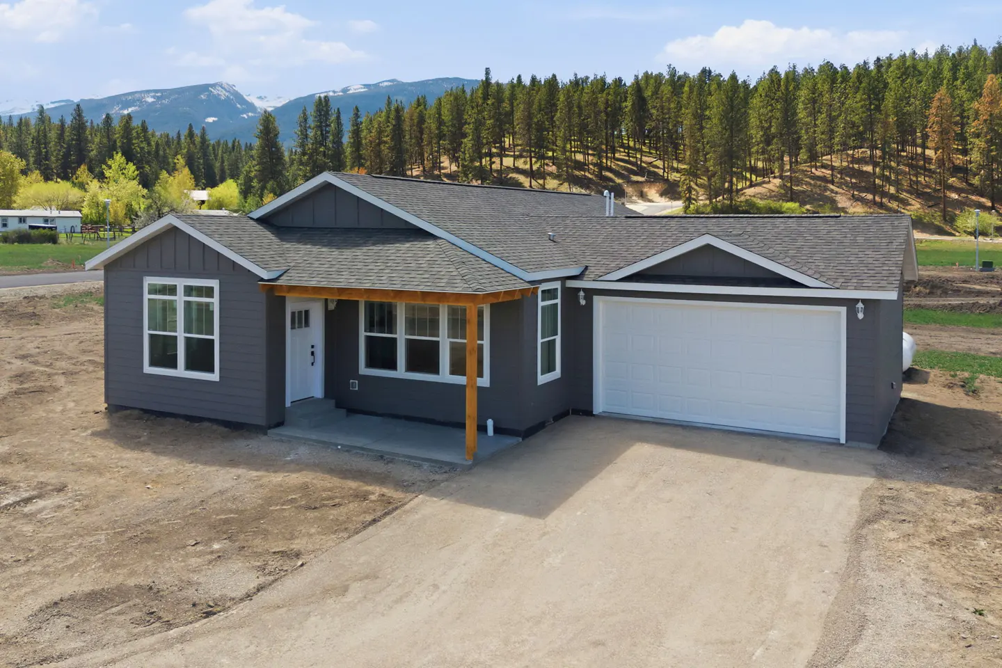 A gray single-story house with a white garage door and a mountain backdrop.