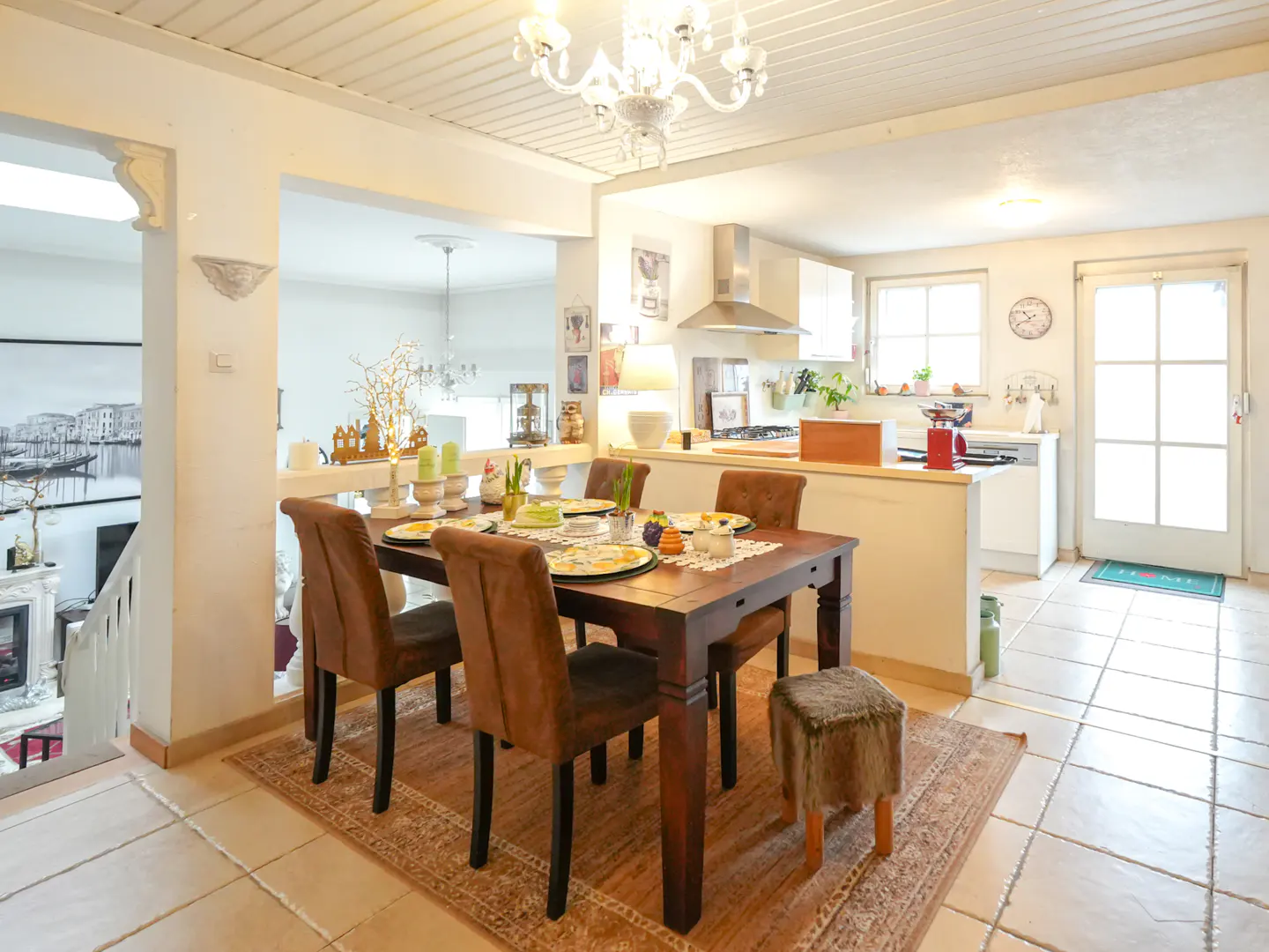 Open-concept dining and kitchen area with a dark wood table, brown chairs, and a white kitchen with stainless steel appliances.
