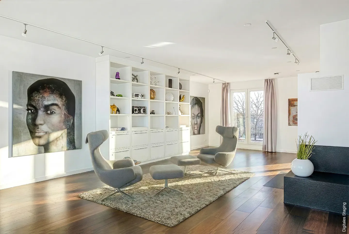 Bright living room with hardwood floors, two gray chairs, a white bookshelf, and a large portrait on the wall.