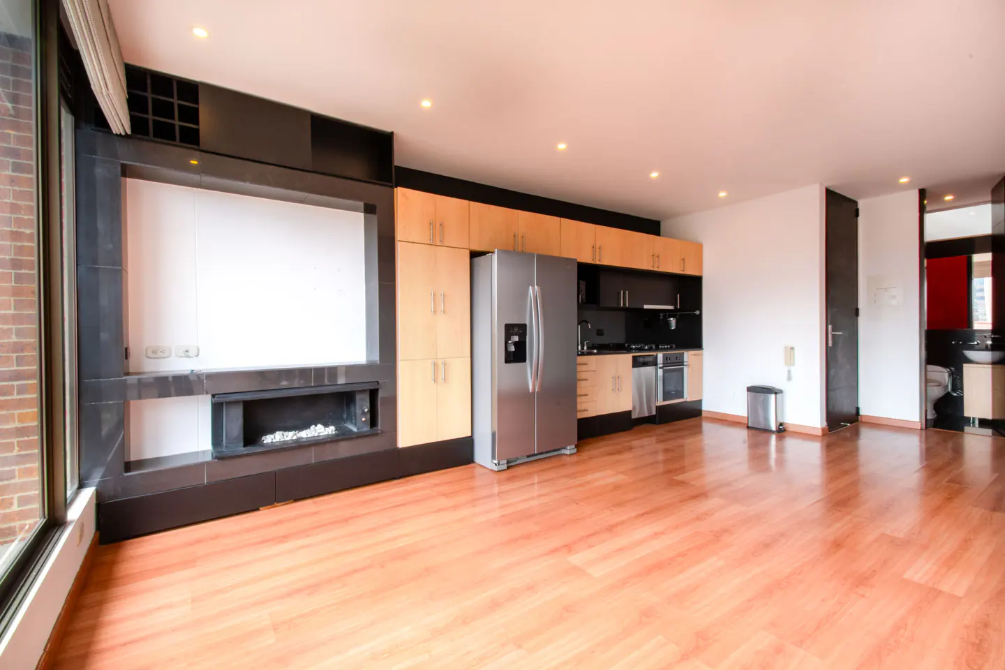 Open-concept kitchen and living area with wood floors, stainless steel appliances, and a modern fireplace.