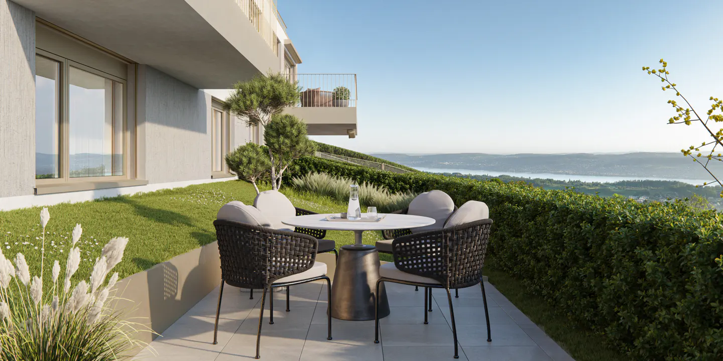 Outdoor patio with a round table and four chairs overlooking a scenic view of a lake and green hills.