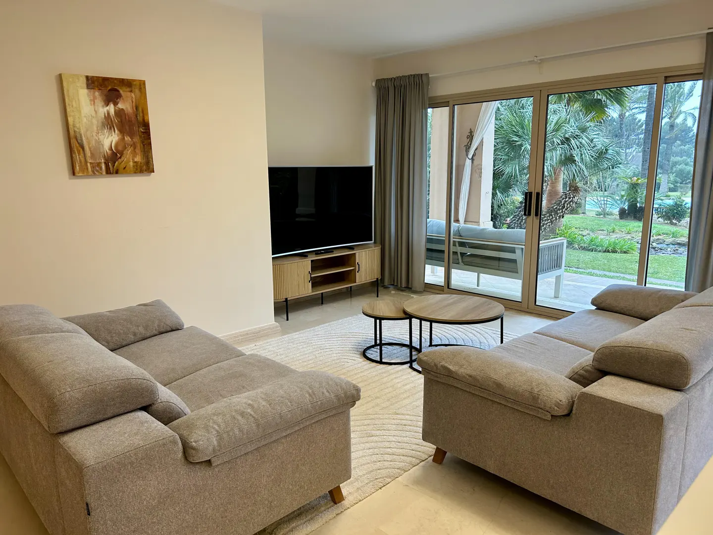 Living room with two gray sofas, a TV, and a sliding glass door to a patio and garden.