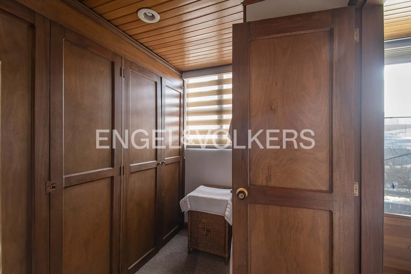 A walk-in closet with wood paneling, a laundry basket, and an open door.