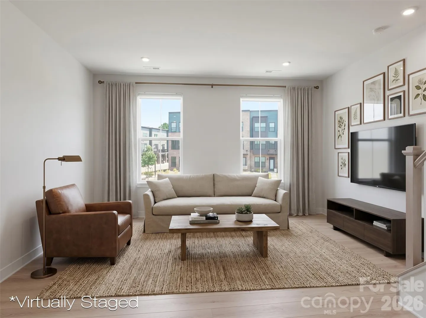 Virtually staged living room with a beige sofa, brown leather armchair, wood coffee table, and wall-mounted TV.