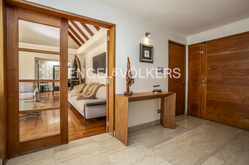 A home's entryway with marble floors, a wooden console table, and a glimpse into the living room with a sofa.