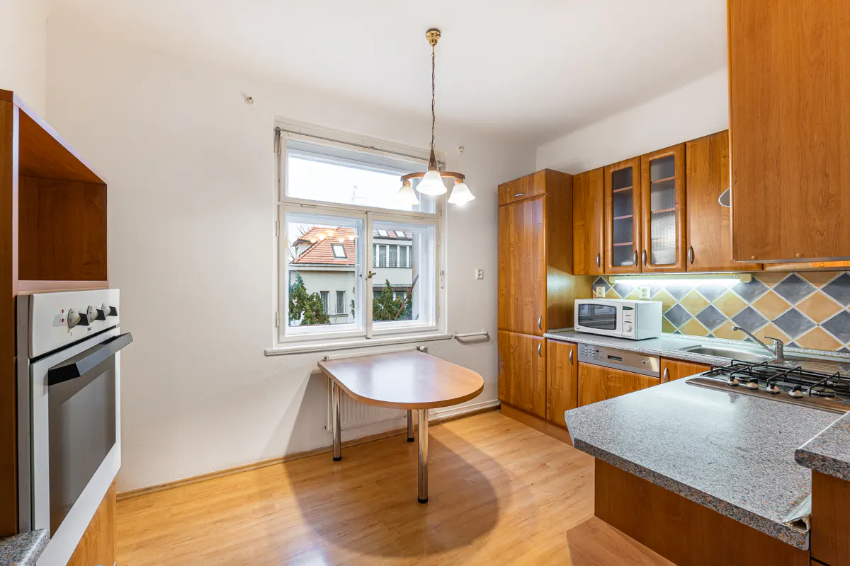 Kitchen with wooden cabinets, granite countertops, built-in oven, microwave, and a small dining table by the window.