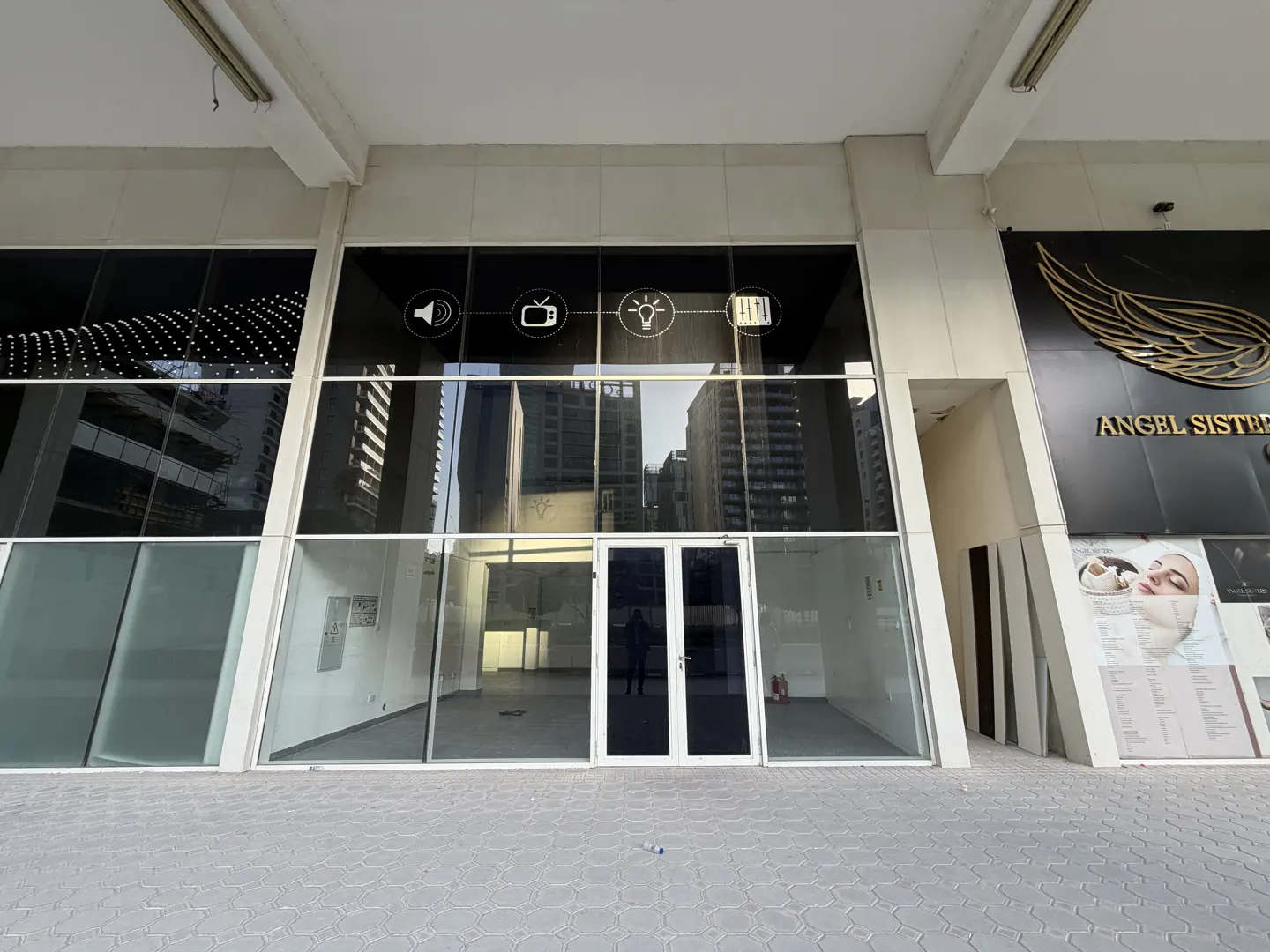 Storefront with large glass windows and a double door entrance. Icons above the windows. "Angel Sisters" sign on the right.