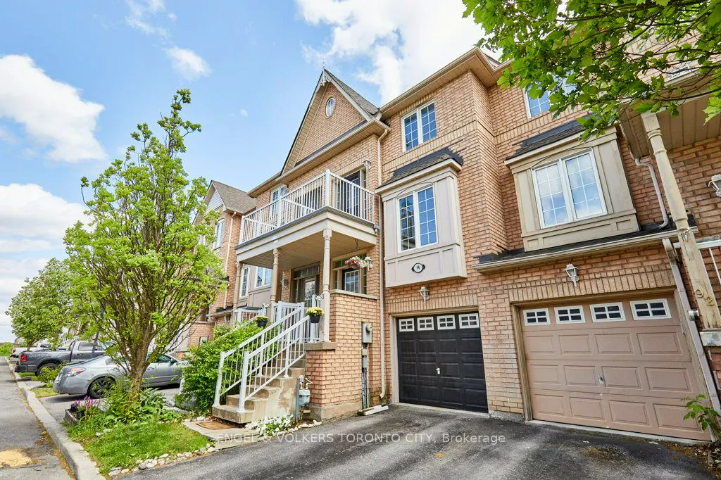 Exterior view of a three-story brick townhouse with a black garage door, a beige garage door, and a second-floor balcony.