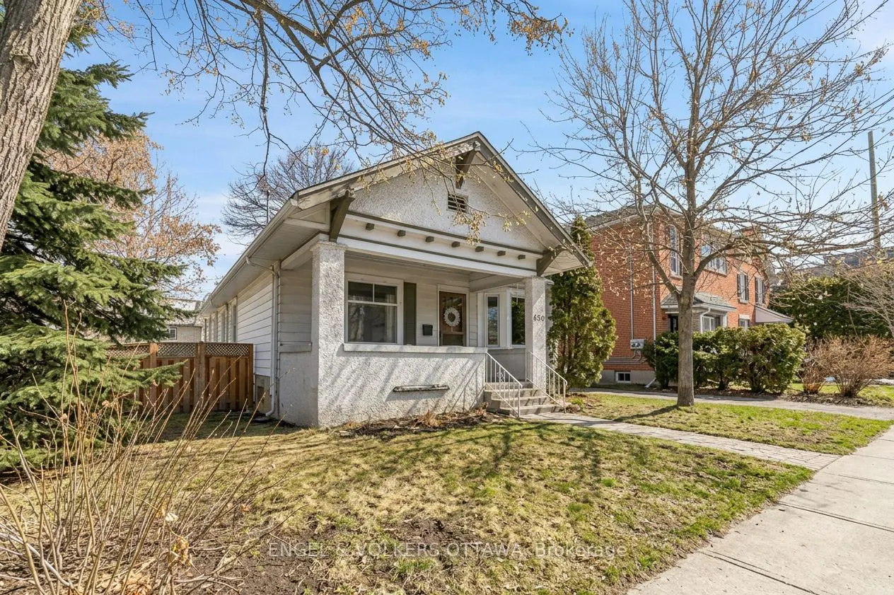 A white, one-story house with a porch and a small lawn on a sunny day.