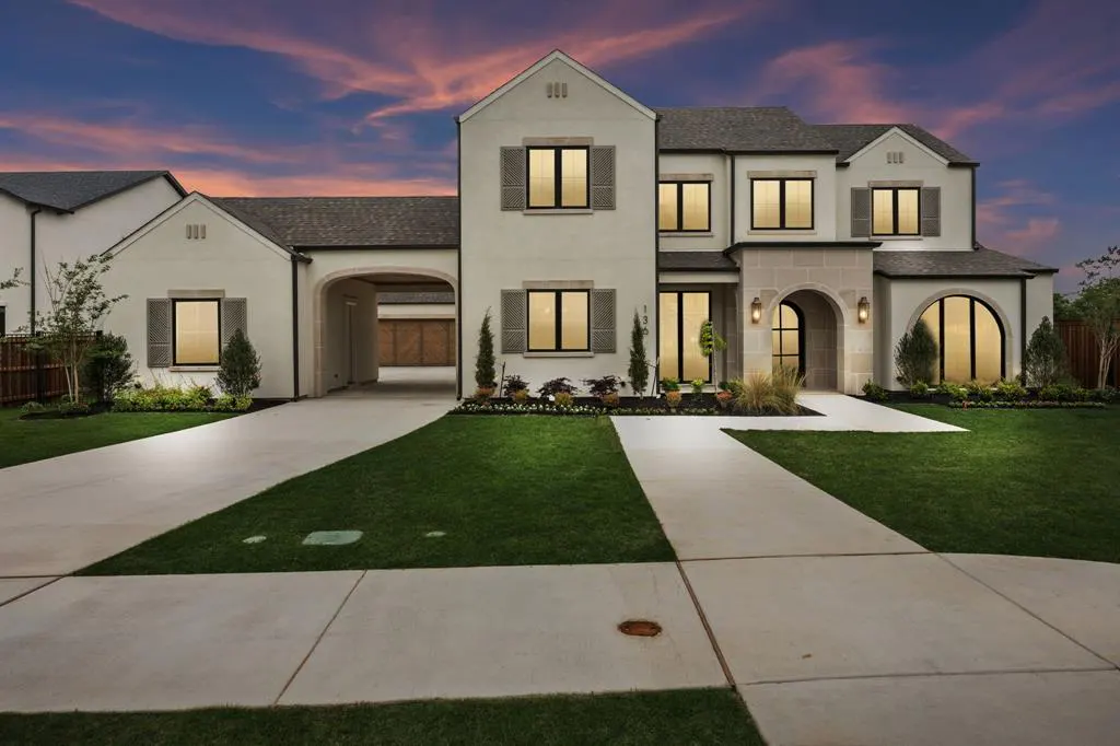 Two-story white house with black framed windows and shutters, a gray roof, and a driveway leading to a garage.