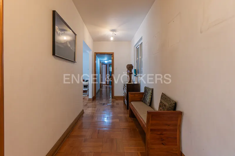 Hallway with parquet flooring, white walls, a wooden bench with pillows, and a framed picture on the wall.