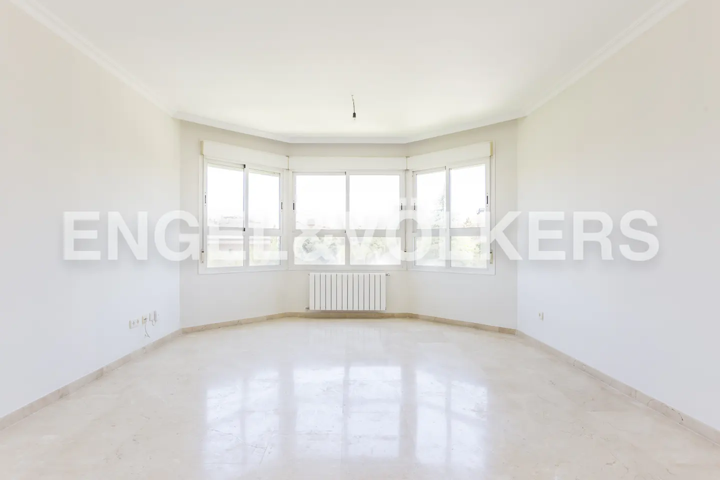 Bright, empty room with white walls, marble floor, and a bay window with a radiator.