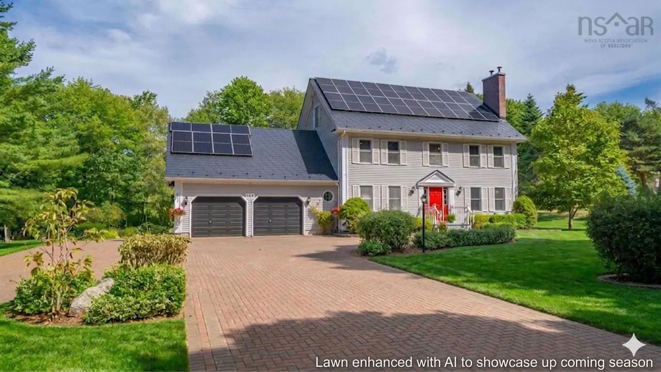 Two-story gray house with a red door, black garage doors, and solar panels on the roof. Brick driveway and green lawn.