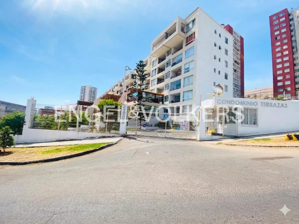 Exterior view of Condominio Terrazas, a white multi-story building with balconies, under a blue sky. The entrance has a white gate and Engel & Volkers signage.