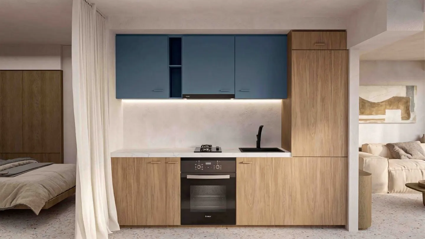 A modern kitchen with blue cabinets above, wood cabinets below, and a black oven. A bedroom and living room are visible in the background.