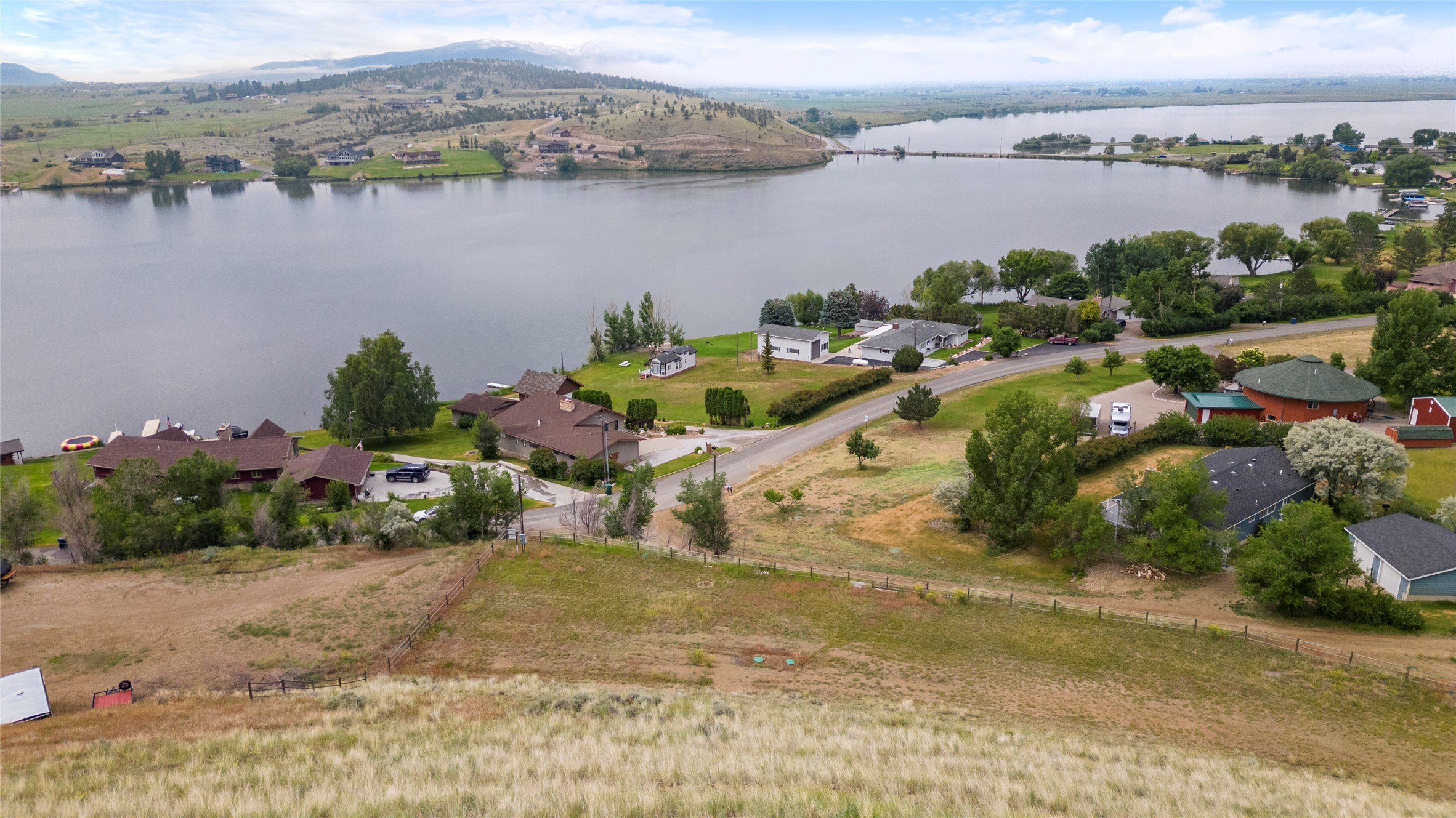 Aerial view of homes near a lake, with mountains in the background under a cloudy sky.