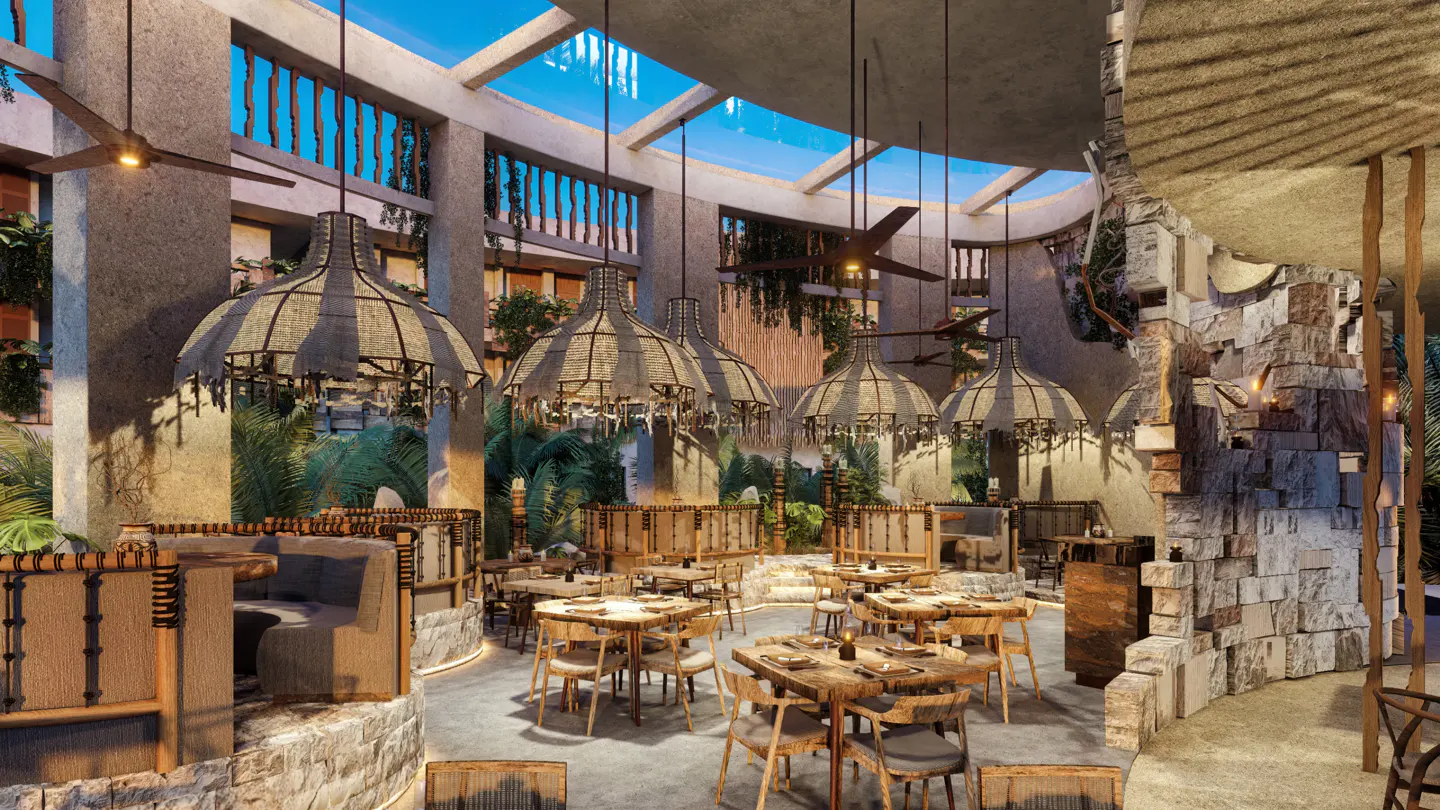 Indoor restaurant with wooden tables, chairs, and straw light fixtures. Stone walls and greenery surround the space.