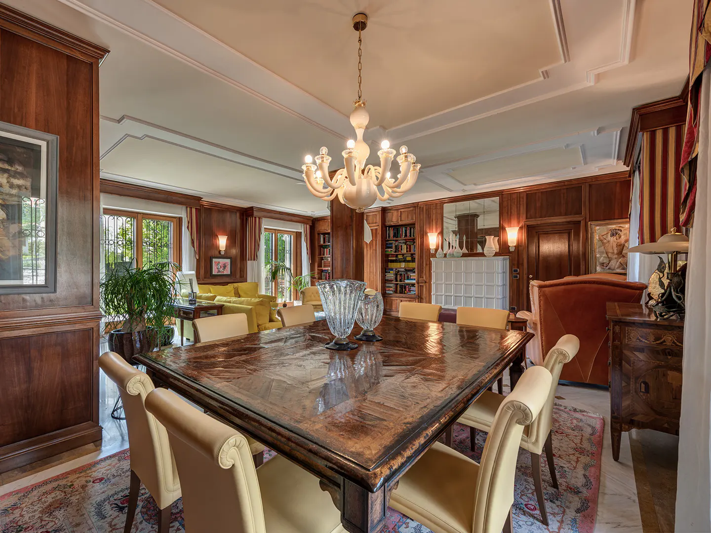 A dining room with wood paneling, a large table with chairs, and a chandelier.