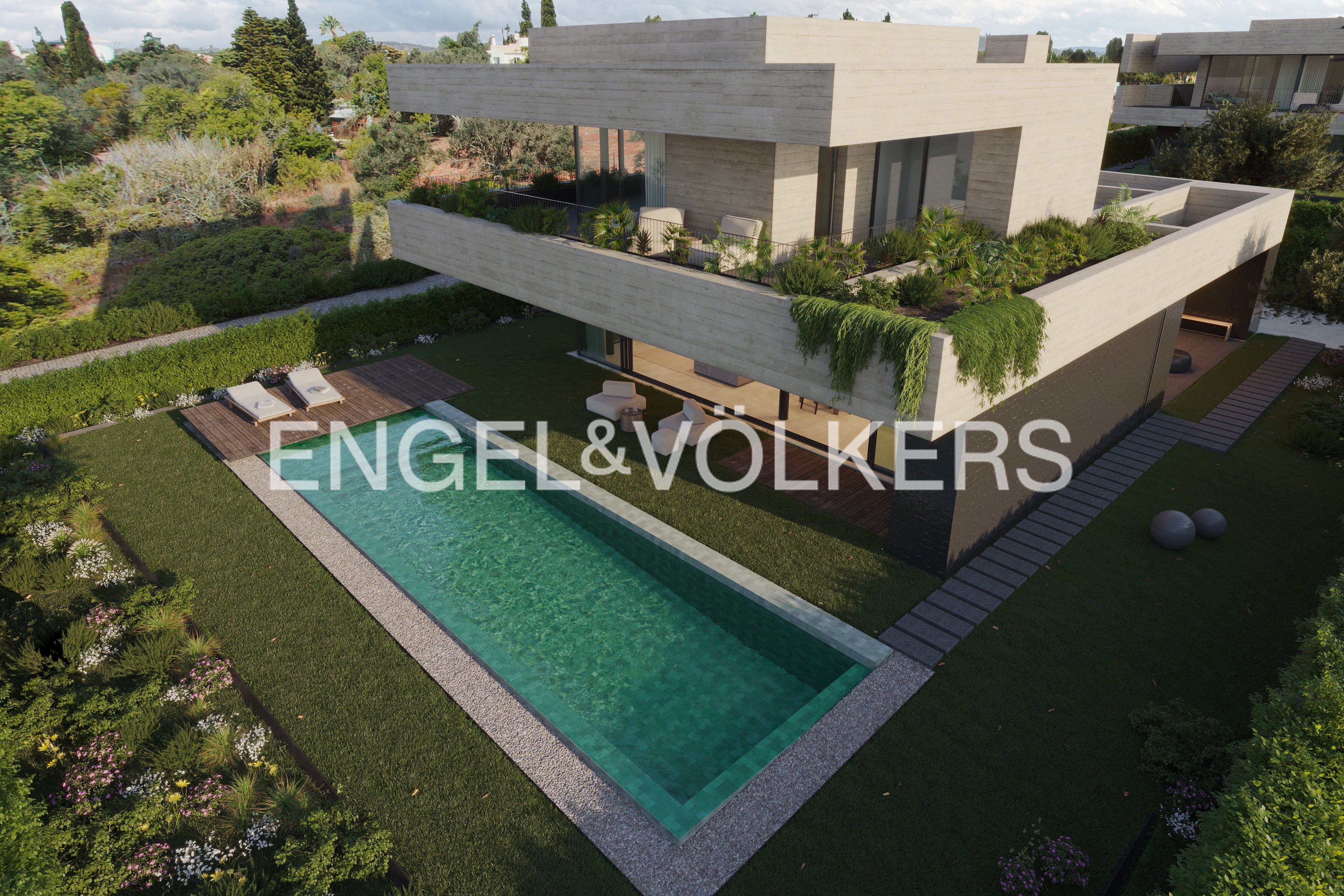 Aerial view of a modern, two-story concrete house with a green lawn and a rectangular swimming pool.