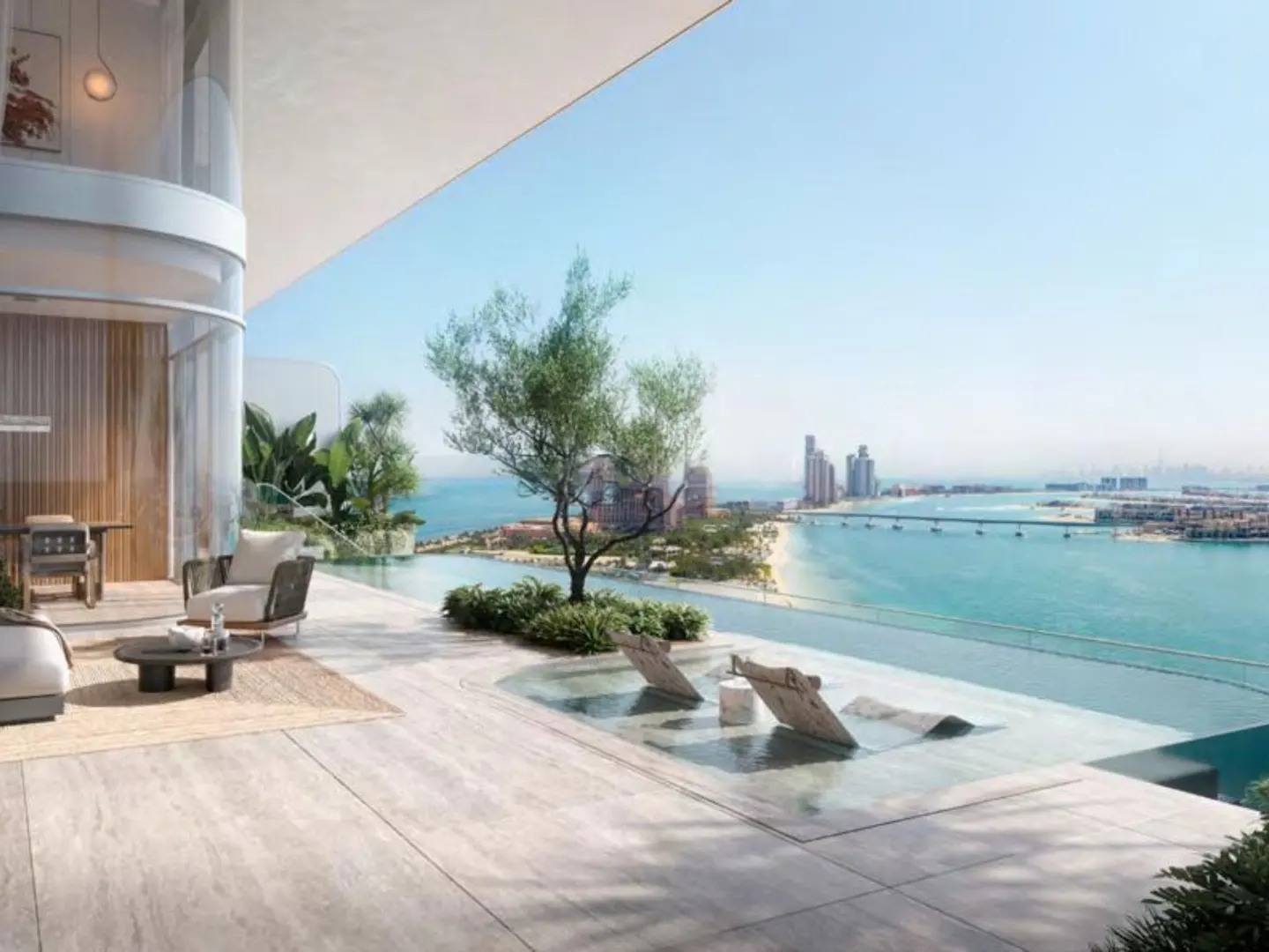 Luxury condo balcony with ocean view. Lounge chairs sit in shallow water. Palm Jumeirah and Dubai skyline in the distance.