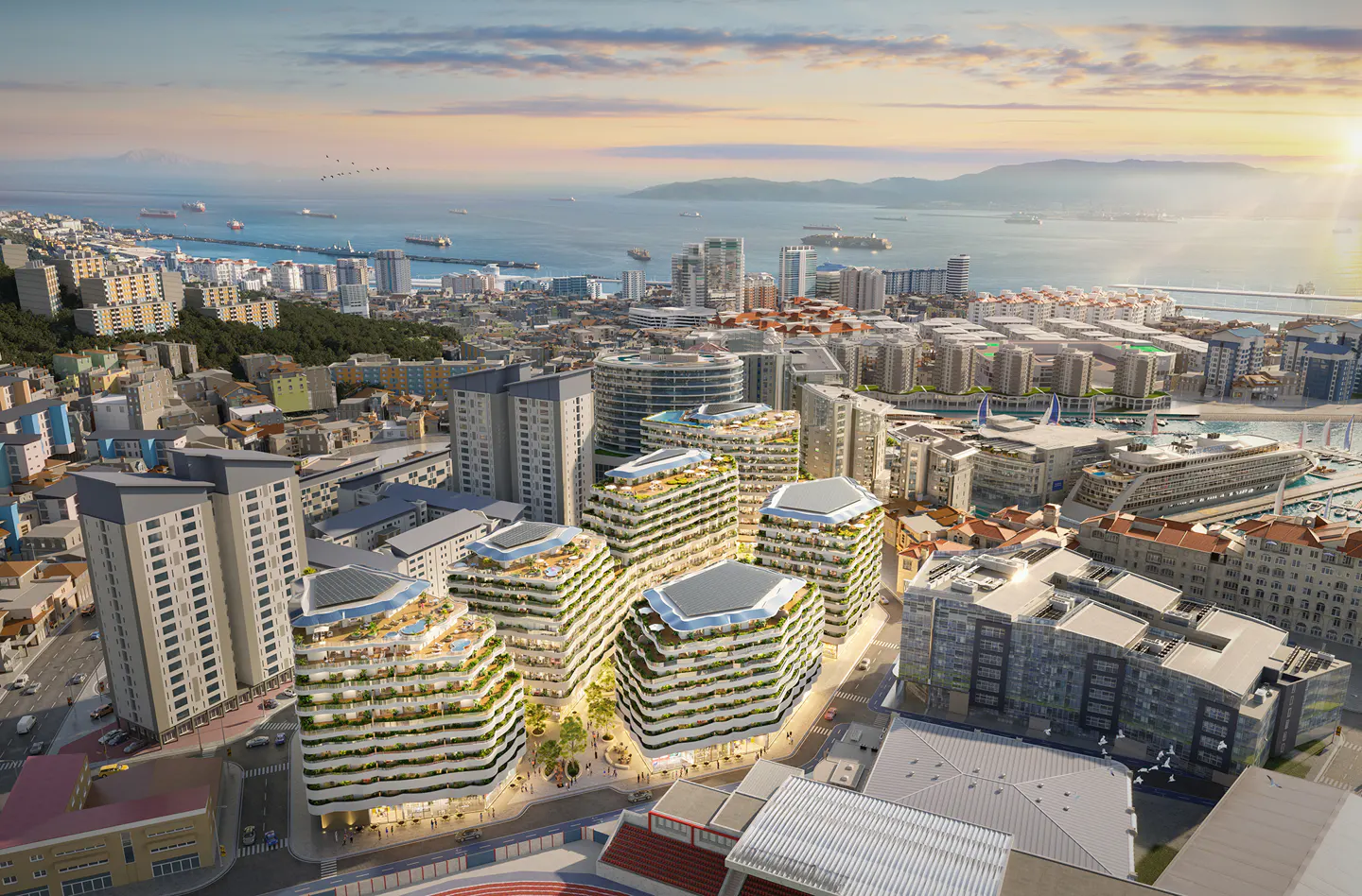 Aerial view of Gibraltar cityscape with modern white buildings, ocean, and sunset.