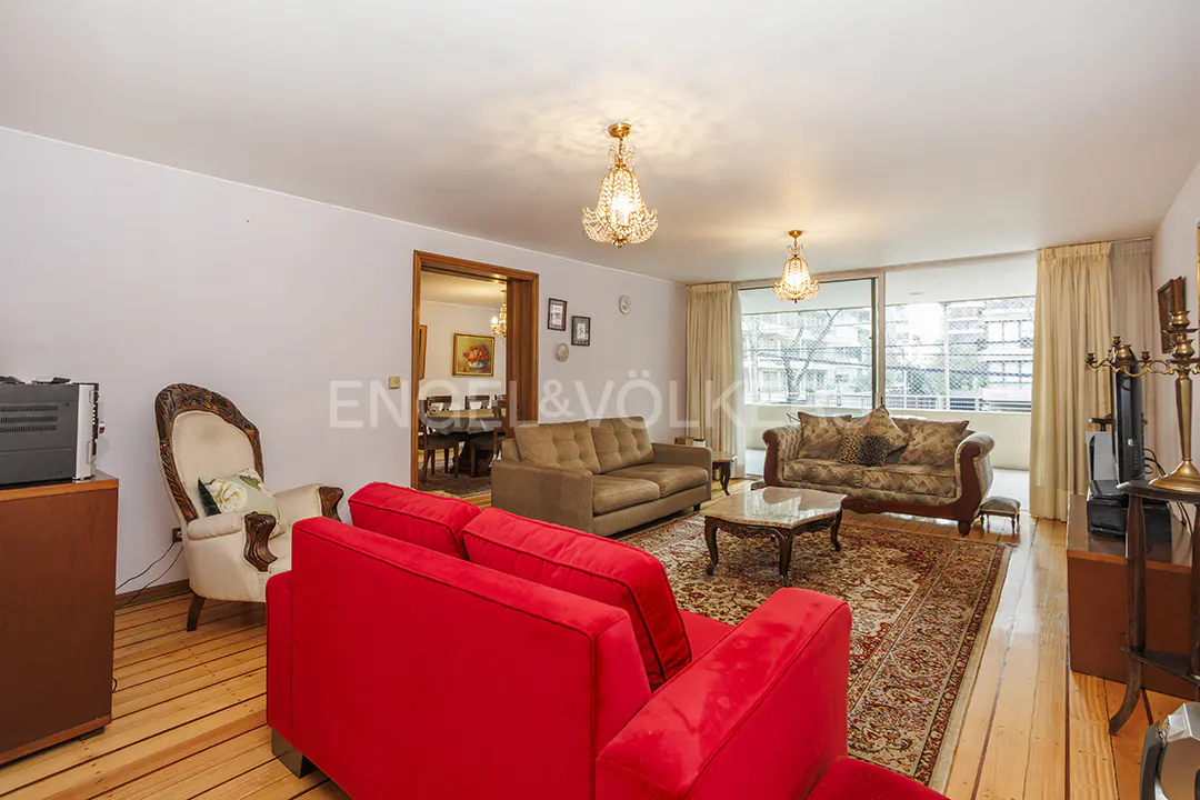 A living room with a red sofa, a brown sofa, and a patterned sofa on a patterned rug.