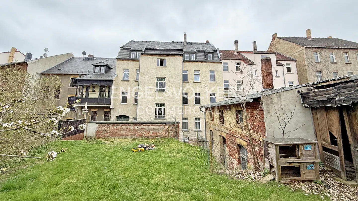 Exterior view of multi-story buildings with brick and beige facades, a grassy hill, and a cloudy sky.