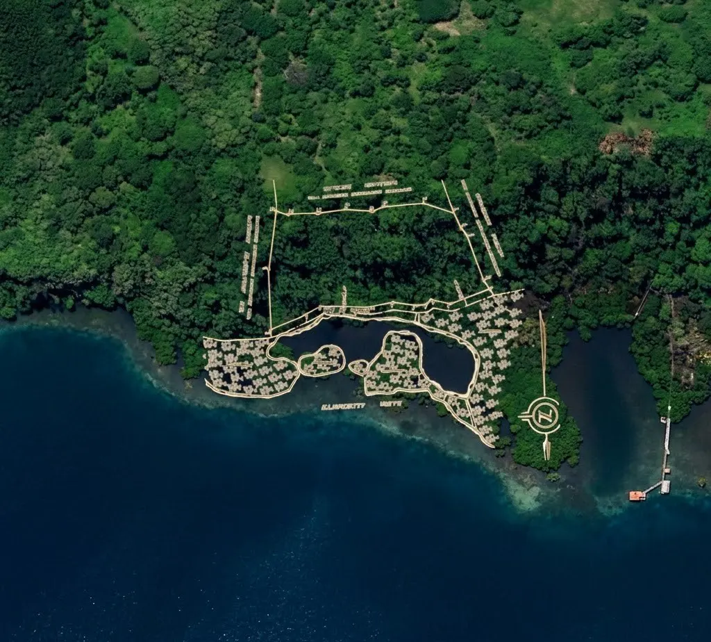 Aerial view of a resort with villas on the water, surrounded by lush green forest and blue ocean. A helipad is visible on a nearby island.