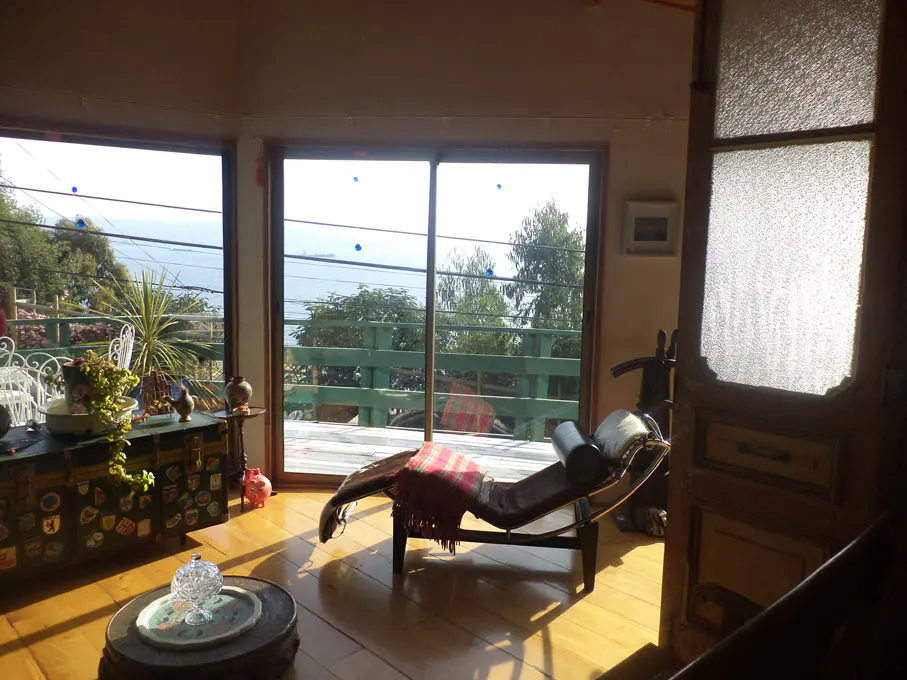 Living room with a chaise lounge, wooden floors, and a view of the ocean through large windows.