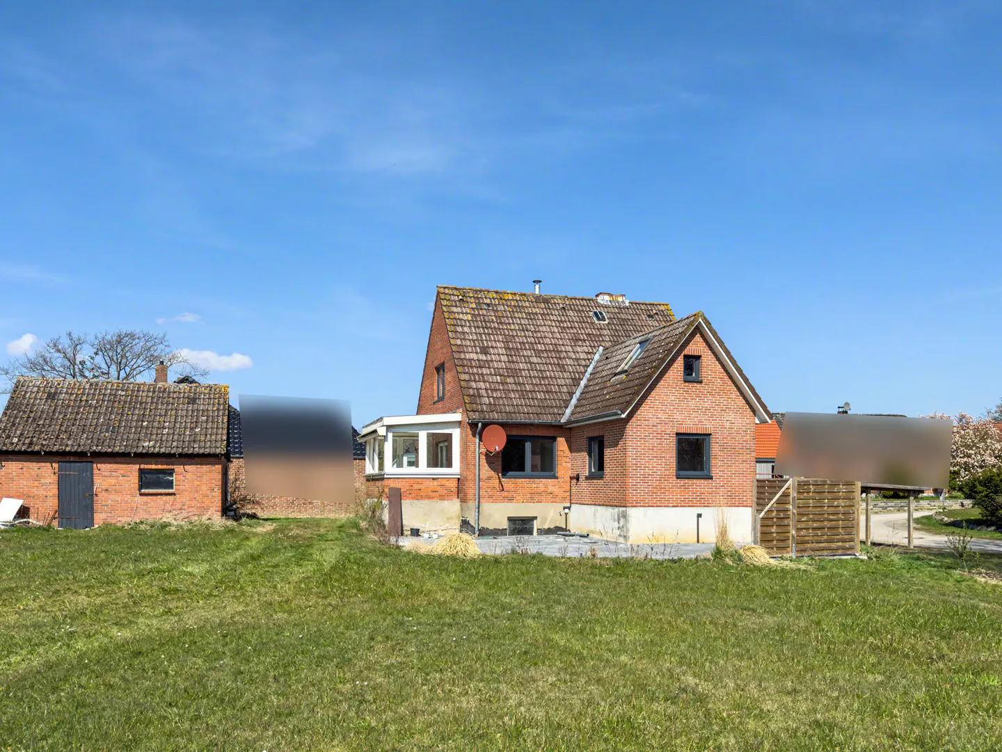 Exterior view of a red brick house with a brown tiled roof and green lawn under a blue sky.