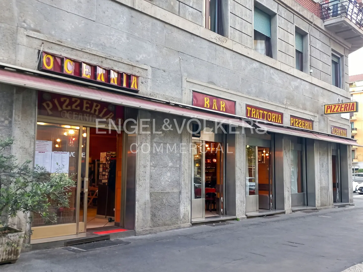 Exterior view of Oceania Pizzeria, Bar, and Trattoria in a gray stone building with red and yellow signage.