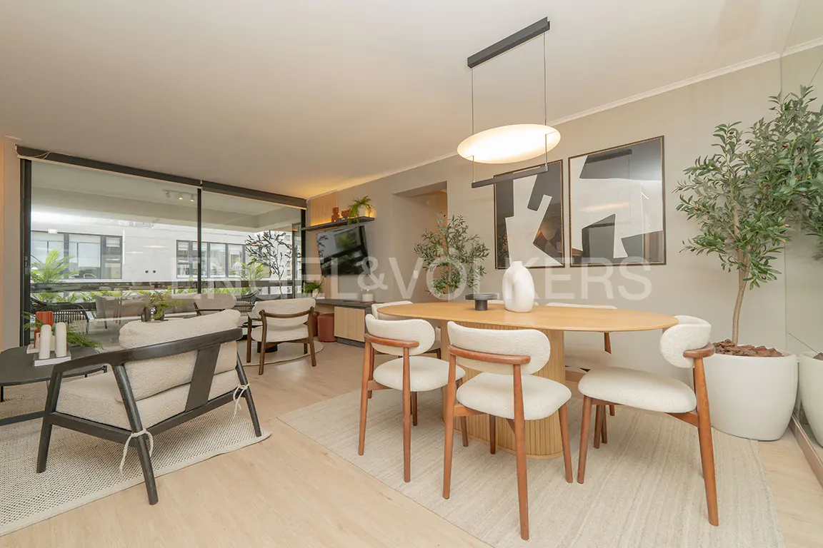 Bright, modern living and dining area with wood floors, neutral furniture, and a large window overlooking a green space.