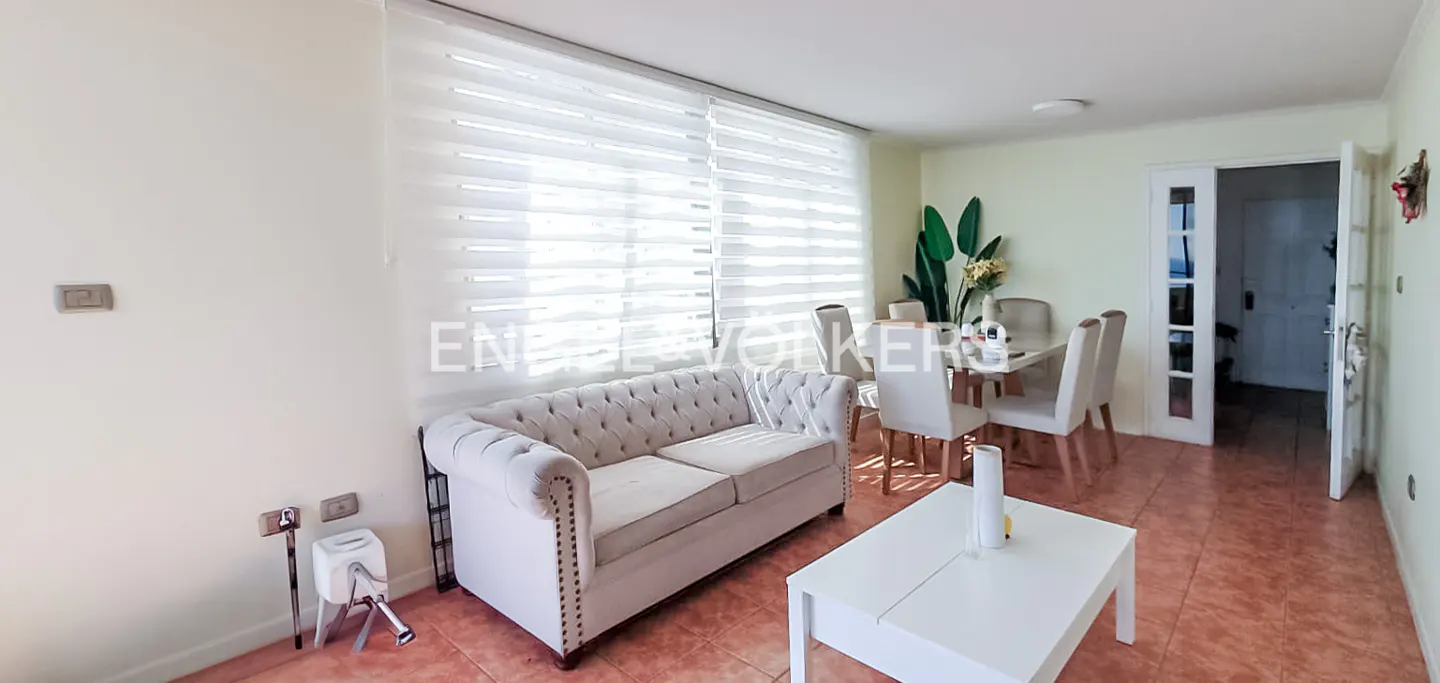Living room with a beige tufted sofa, white coffee table, dining set, and light-filtering blinds.