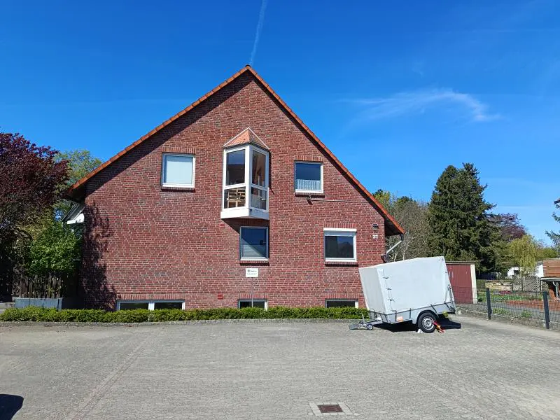 A two-story brick house with a trailer parked in the driveway on a sunny day.