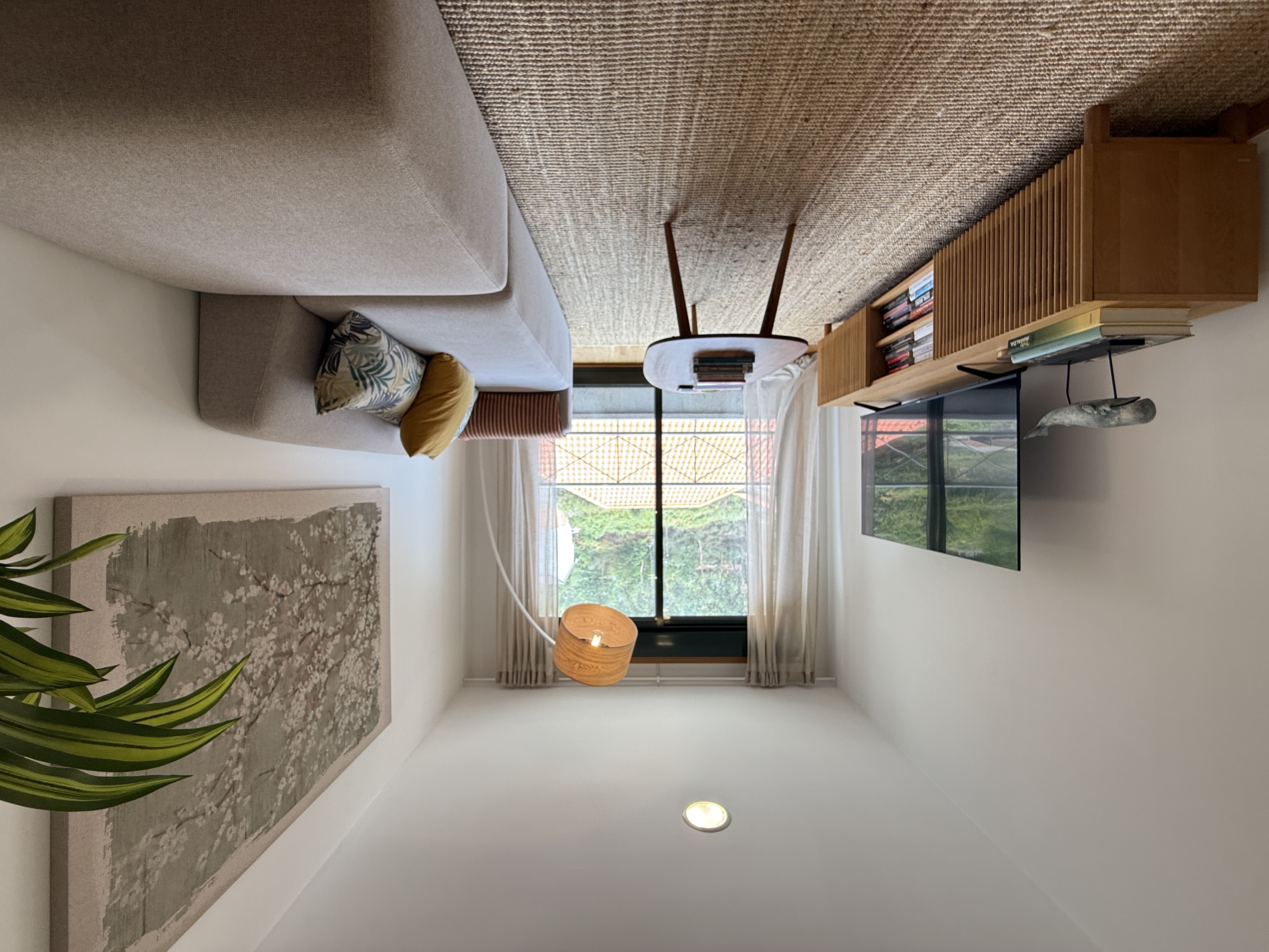 Modern living room with a beige sofa, wooden media console, TV, coffee table, and a large floral wall art piece.