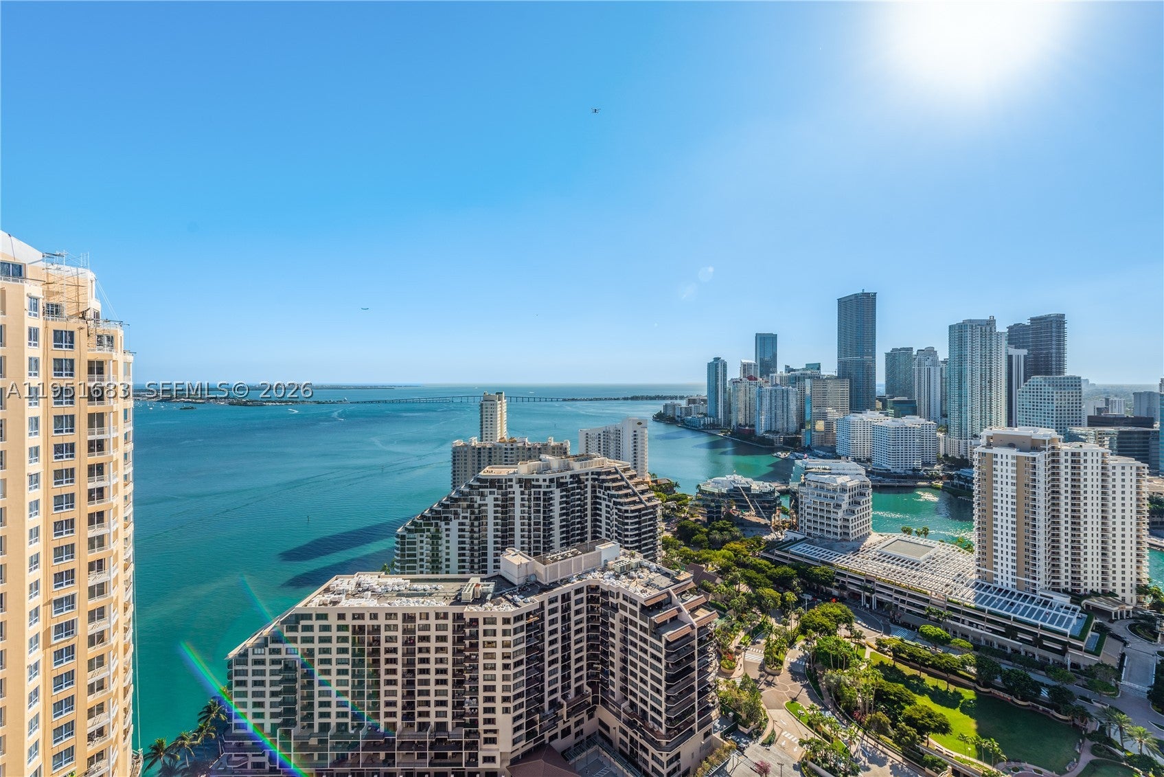 High-angle view of Miami skyline and turquoise bay with modern high-rise buildings under a bright, clear blue sky. [AI-generated text]