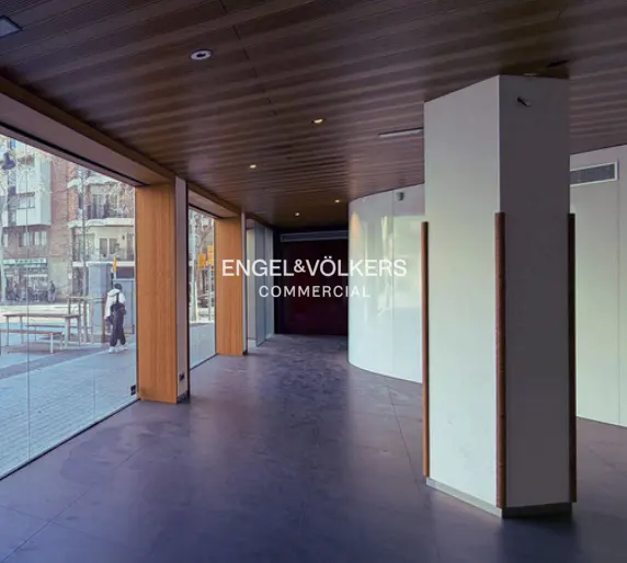 Empty commercial space with wood ceiling, large windows, and white columns. "Engel & Völkers Commercial" logo is visible.