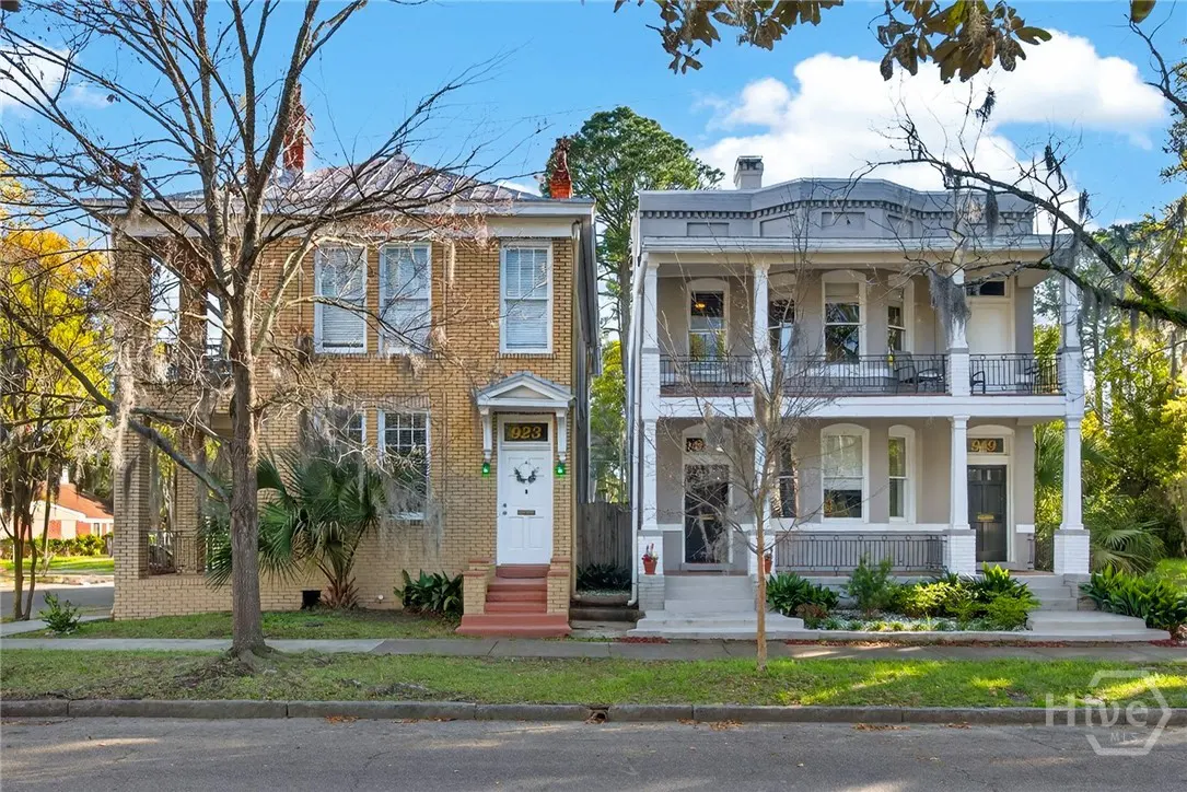 Two-story houses stand side-by-side. The left is brick with a white door, and the right is gray with white columns.