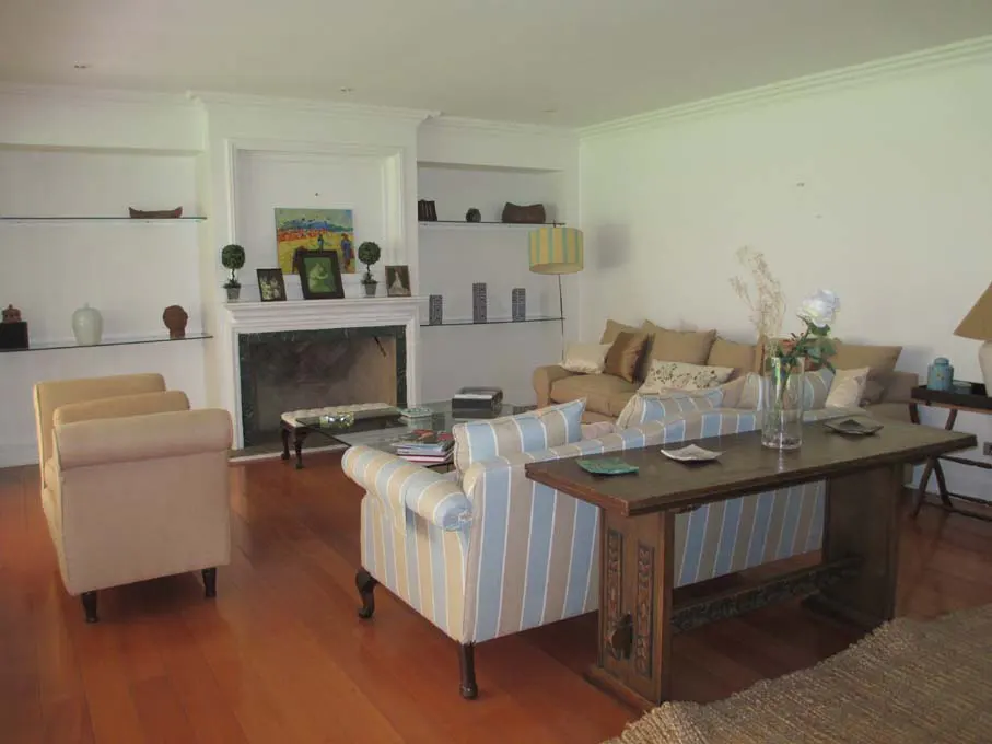 Living room with hardwood floors, fireplace, built-in shelves, and furniture including sofas, chairs, and a wooden table.