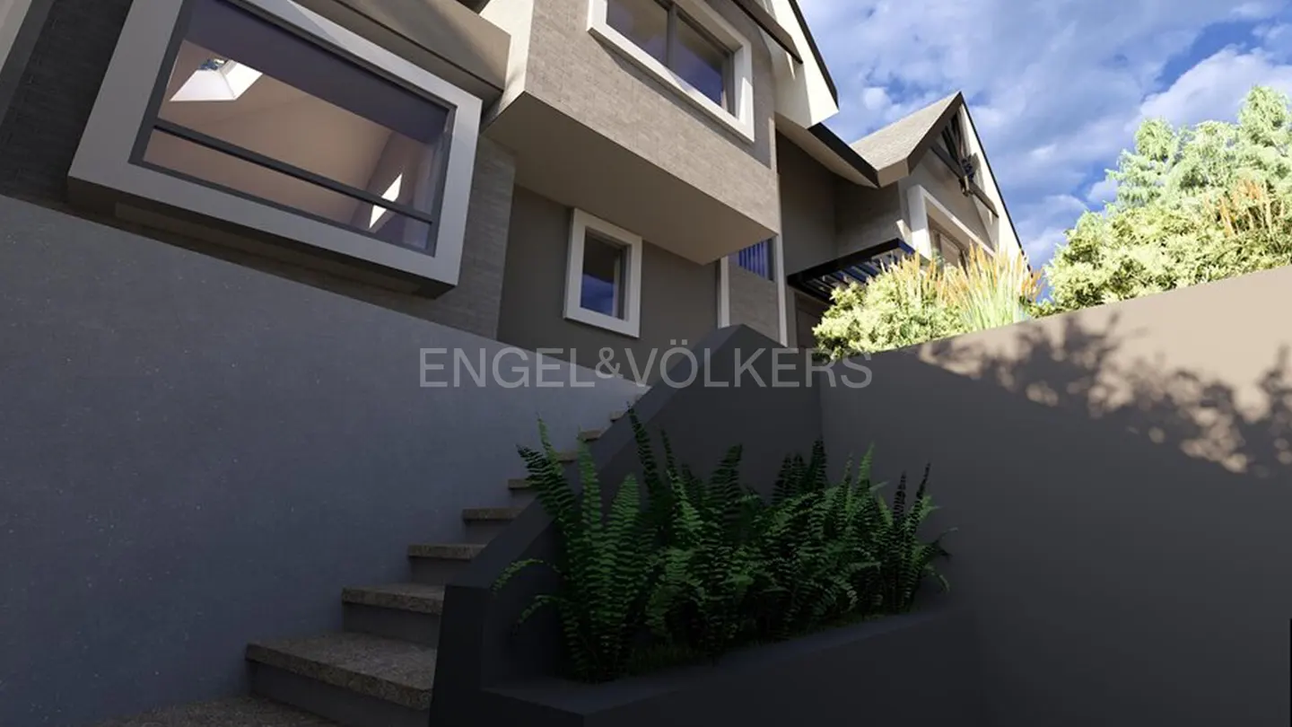 Exterior view of a modern gray house with stairs leading up to the entrance, and the Engel & Völkers logo.