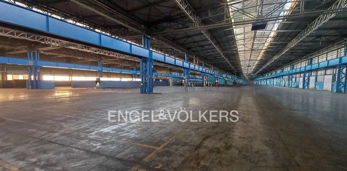 A large, empty warehouse with blue support beams and a concrete floor.