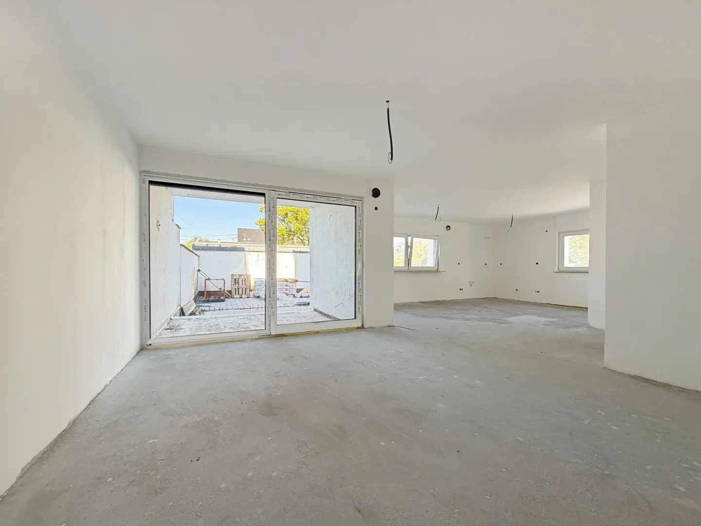 Unfinished room with white walls, a concrete floor, and a sliding glass door to the outside.
